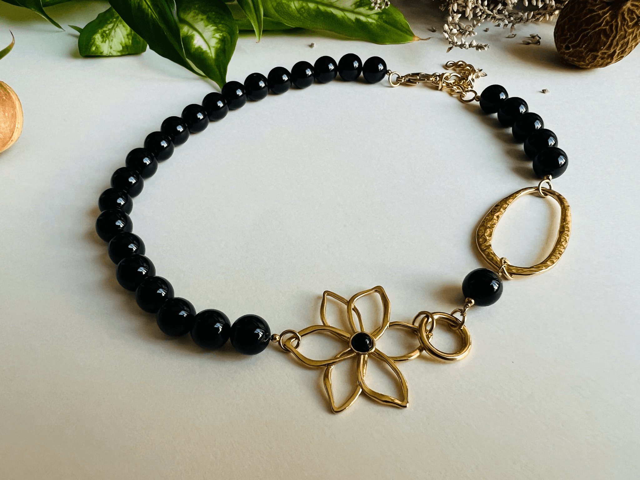 Collier asymétrique MARYLENE perles noires et fleur dorée - Créations Uniques